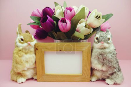 Easter Background decoration with rabbit doll and tulip flower bouquet on pink background