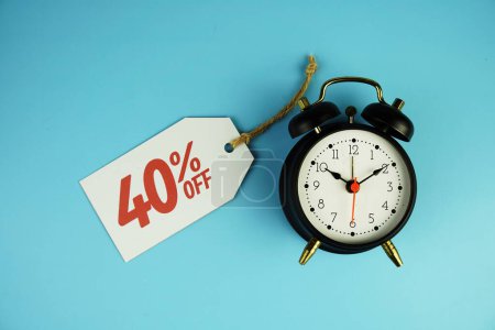 Top view of Sale 40% text on tag sale with black alarm clock flat lay on blue background