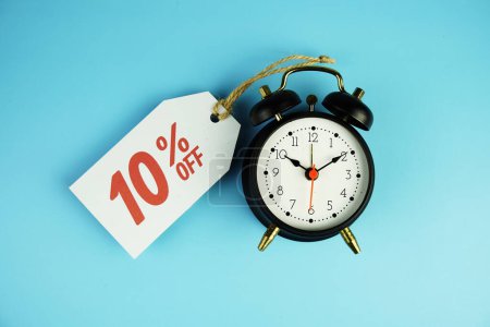 Top view of Sale 10% text on tag sale with black alarm clock flat lay on blue background