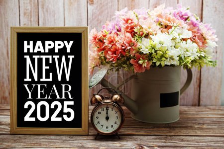 Foto de Feliz Año Nuevo 2025 tipografía texto en pizarra con despertador y flor en jarrón de riego - Imagen libre de derechos