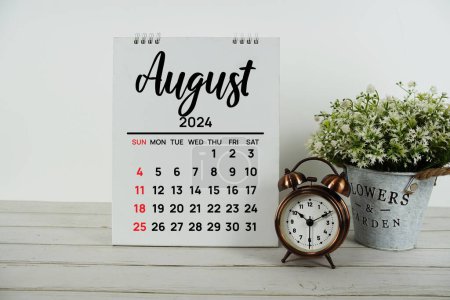 August 2024 monthly calendar with vintage alarm clock on wooden background