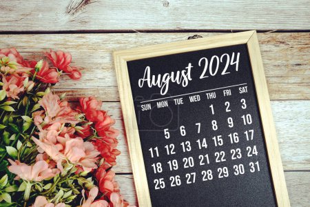 August 2024 Monatskalender mit Blumenstraußdekoration auf Holzgrund