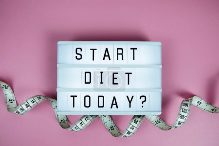 Start diet today? letterboard text on LED Lightbox and Measuring tape on pink background, Healthcare concept