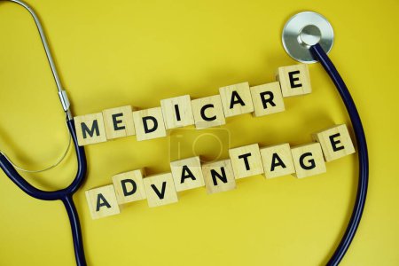 Avantage Medicare avec des blocs de bois alphabet lettres et stéthoscope sur fond jaune