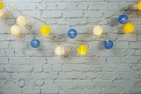 Bunte LED-Baumwollball dekorativ hängen auf weißem Backstein Wand Hintergrund