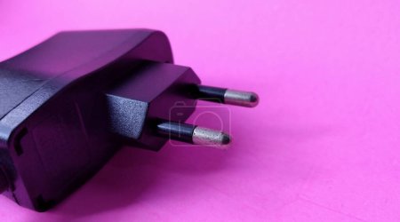 Black power plug on a pink background. Copy space for text.