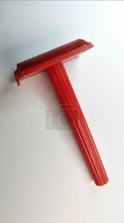 Red plastic shaving razor on a white background, closeup of photo