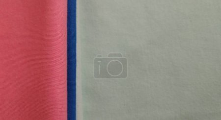 Fabric samples in different shades of blue and pink, closeup on green background