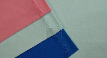 Fabric samples in different shades of blue and pink, closeup on green background