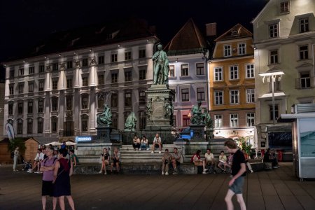 Téléchargez les photos : Graz, Autriche - 26 août 2023 : Vue de nuit de la place principale, avec la fontaine de l'archiduc John Brunner - en image libre de droit