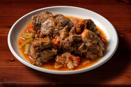 Isolated Bowl with a portion of oxtail stewed vaccinara on wooden background