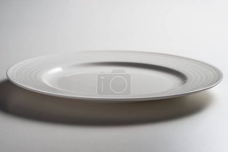 Empty white dinner plate with edge decorated with concentric circles in relief isolated on white background