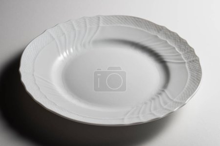 Empty white dinner plate with elegant classic decorations isolated on white background