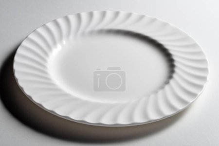 Empty white dinner plate with wavy relief edge isolated on white background