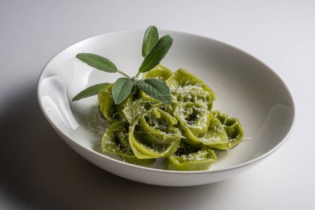 Nudelschüssel mit grünen Ravioli mit Salbei und Parmesan auf weißem Hintergrund