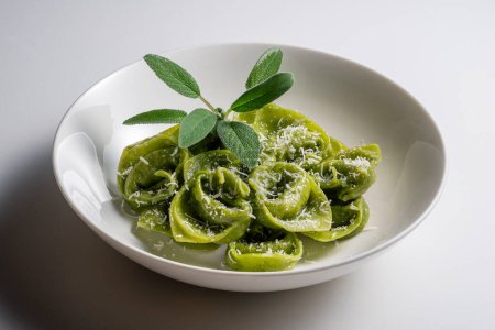 Pasta Bowl of green ravioli with sage and parmesan on white background