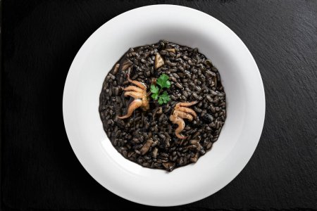 Draufsicht auf Risotto-Gericht mit Tintenfischtinte auf schwarzem Stein