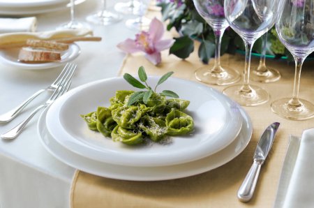 Nudelschüssel mit grünen Ravioli mit Salbei und Parmesan auf gedecktem Tisch