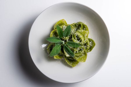 Top view of Pasta Bowl of green ravioli with sage and parmesan on white background