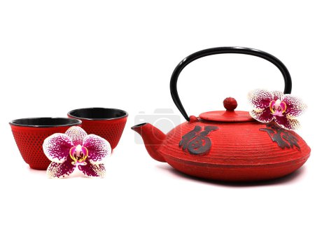Photo for Red cast iron teapot with 2 teacups, decorated with phaleonopsis orchid flowers. Isolated on a white background. - Royalty Free Image