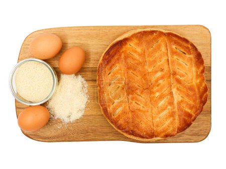 Téléchargez les photos : Gâteau à l'épiphanie avec œufs et poudre d'amande sur une planche en bois. Gâteau au Frangipane en vue sur fond blanc. - en image libre de droit