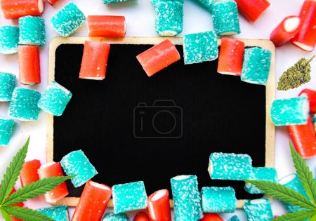 Photo for Cannabis products flat lay buds and gummy candies on chalk board with copy space - Royalty Free Image