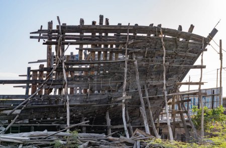 Abandoned ship structure with weathered beams and barren landscape