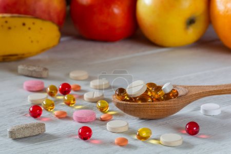 Different pills and vitamins on the background of fresh fruits