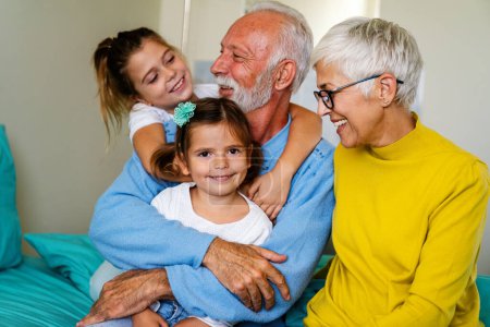 Foto de Feliz familia visitando a un paciente masculino mayor en la cama del hospital. Asistencia sanitaria, apoyo, concepto familiar - Imagen libre de derechos