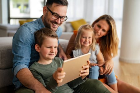 Foto de Concepto de educación en línea familiar de tecnología de dispositivos digitales. Familia joven feliz con dispositivos digitales en casa. - Imagen libre de derechos