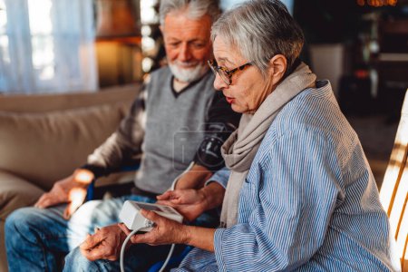 Senior couple at home measuring blood pressure together. Home monitoring people healthcare concept