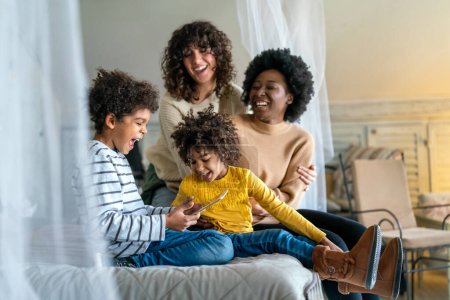 Photo for Happy multiethnic family concept. Smiling gay women couple spending time together with children at home. - Royalty Free Image