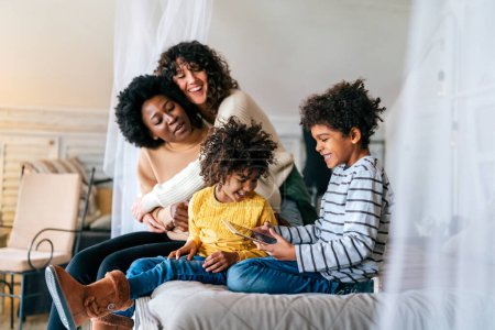 Téléchargez les photos : Joyeux concept de famille multiethnique. sourire gay femmes couple passer du temps avec enfants à la maison. - en image libre de droit