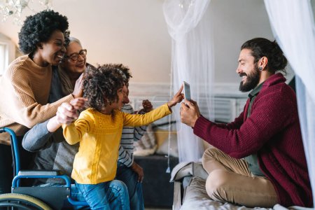 Téléchargez les photos : Heureuse famille multiethnique élargie s'amuser et passer du temps ensemble à la maison. Les gens aiment concept - en image libre de droit