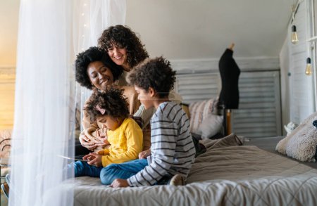 Téléchargez les photos : Joyeux concept de famille multiethnique. sourire gay femmes couple passer du temps avec enfants à la maison. - en image libre de droit