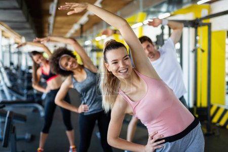 Photo for Group of young fit people, friends smiling and enjoy sport in gym. People exercise, work out concept. - Royalty Free Image