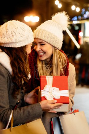 Téléchargez les photos : Portrait de femmes heureuses amies échangeant des cadeaux de Noël en plein air. Fête des fêtes gens bonheur concept - en image libre de droit