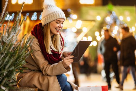 Téléchargez les photos : Portrait de jeune femme heureuse profitant des vacances et achète un arbre de Noël sur le marché décoré - en image libre de droit