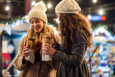Téléchargez les photos : Femmes heureuses amis profiter du temps ensemble dans la ville avec des décorations de Noël en plein air. vacances gens bonheur concept - en image libre de droit