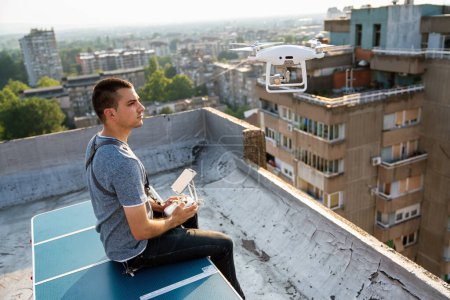 Téléchargez les photos : Jeune technicien homme volant drone UAV avec télécommande en ville en plein air - en image libre de droit