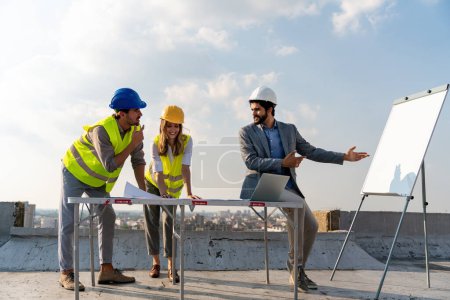 Foto de Team of architects people in group on construction site checking documents and business workflow - Imagen libre de derechos