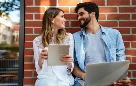 Foto de Happy couple in love using digital devises for work, study or social media. People technology concept - Imagen libre de derechos