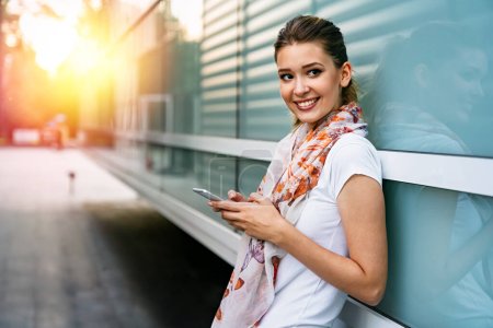 Foto de Hermoso negocio joven, estudiante mujer usando el teléfono móvil al aire libre. Concepto de tecnología de comunicación. - Imagen libre de derechos