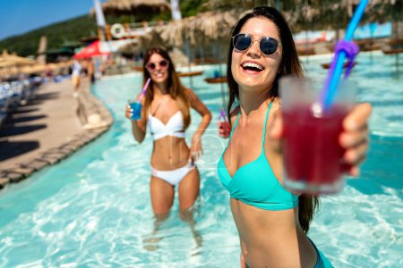 Téléchargez les photos : Les jeunes femmes en maillot de bain avec des cocktails sur la plage profiter des vacances d'été. Paradis tropical escapade voyage tourisme concept. - en image libre de droit