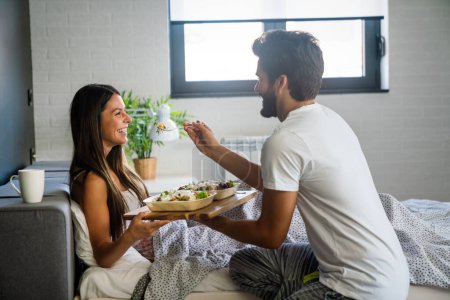 Téléchargez les photos : Man bringing the breakfast to his wife in bed. People, couple, love, food concept - en image libre de droit