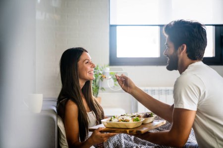 Téléchargez les photos : Happy man apporte le petit déjeuner au lit pour sa belle petite amie. Couple, concept d'amour - en image libre de droit