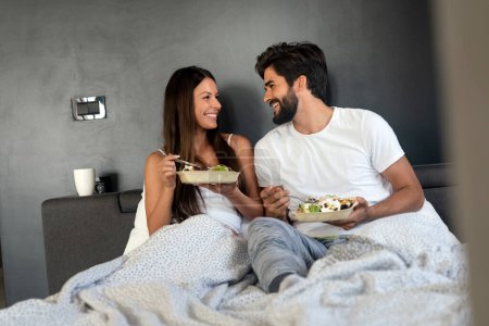 Téléchargez les photos : Couple heureux romantique prenant le petit déjeuner au lit. Amour, personnes, concept alimentaire - en image libre de droit
