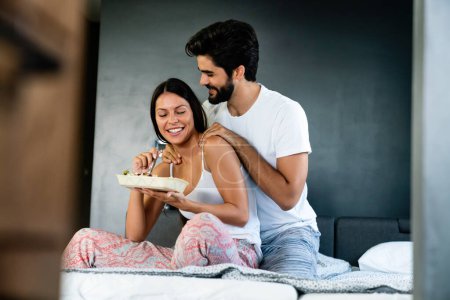 Foto de Romántica pareja feliz desayunando en la cama en casa - Imagen libre de derechos