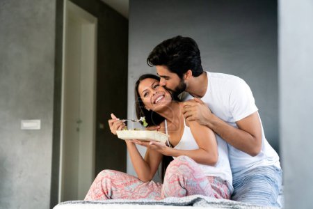 Foto de Desayuno saludable en la cama. Joven hermosa pareja de amor está sentado en la cama y desayunando. - Imagen libre de derechos