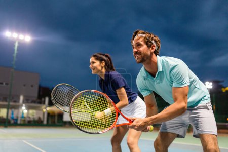 Foto de Pareja joven en pista de tenis. Hombre guapo y mujer atractiva están jugando tenis. Gente concepto deportivo - Imagen libre de derechos